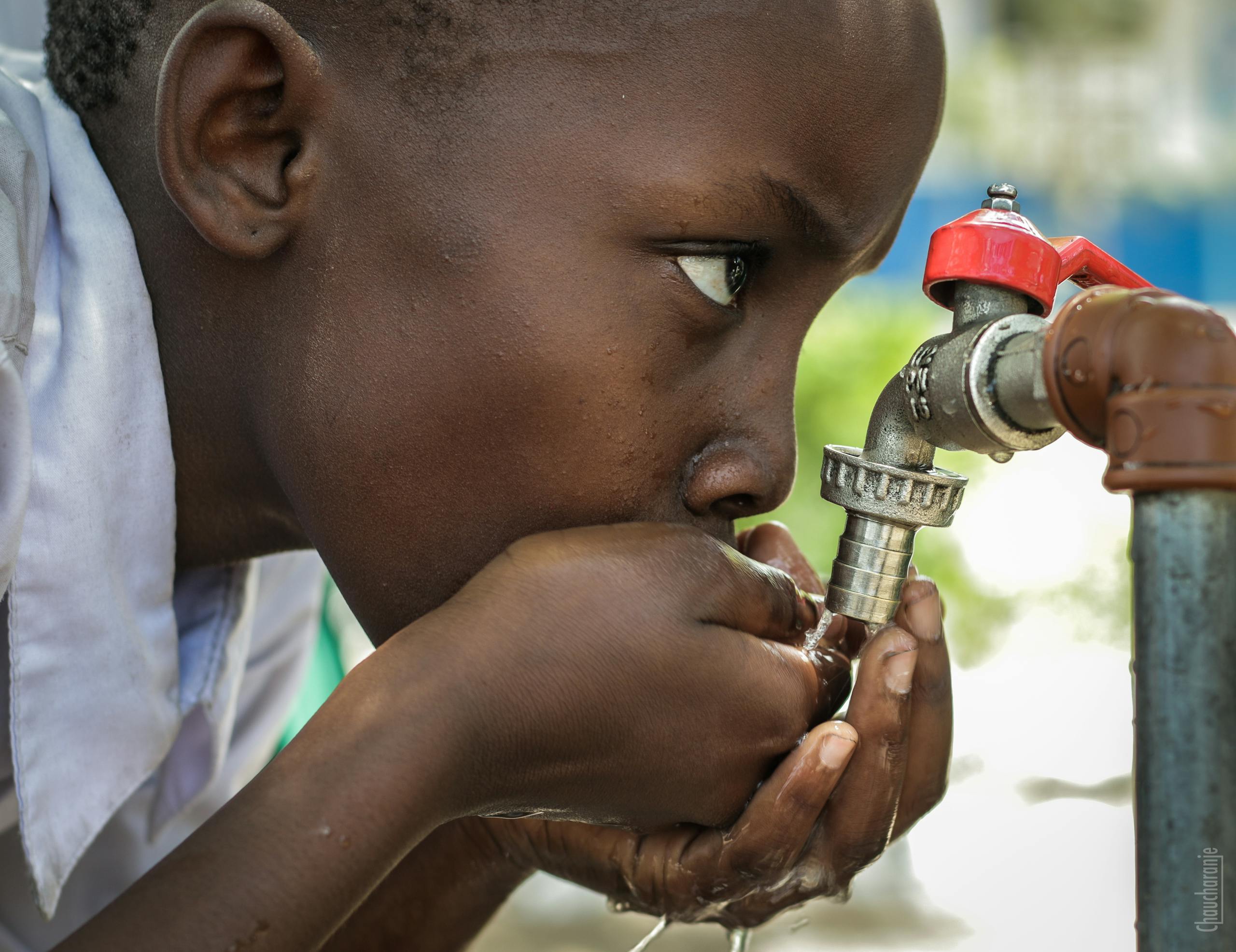 Close-up of a child drinking water from a faucet in Mwanza, Tanzania.