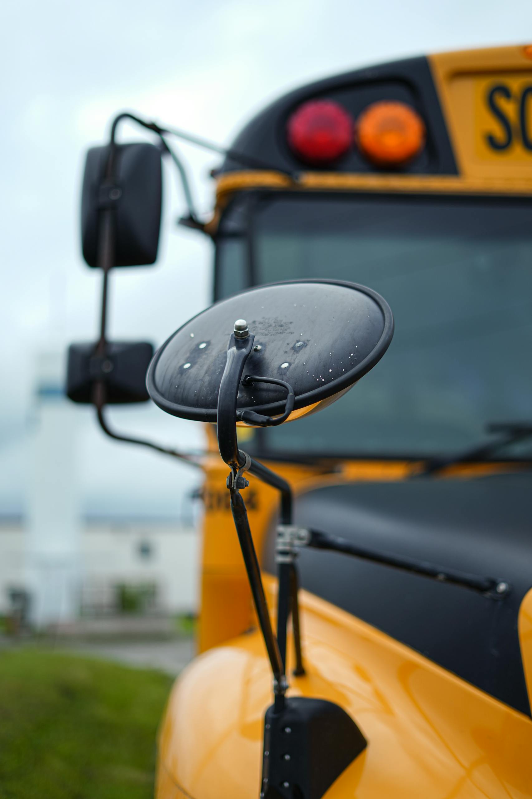 Close-up of a yellow school bus's mirror and front details in Kitchener, Ontario, Canada.