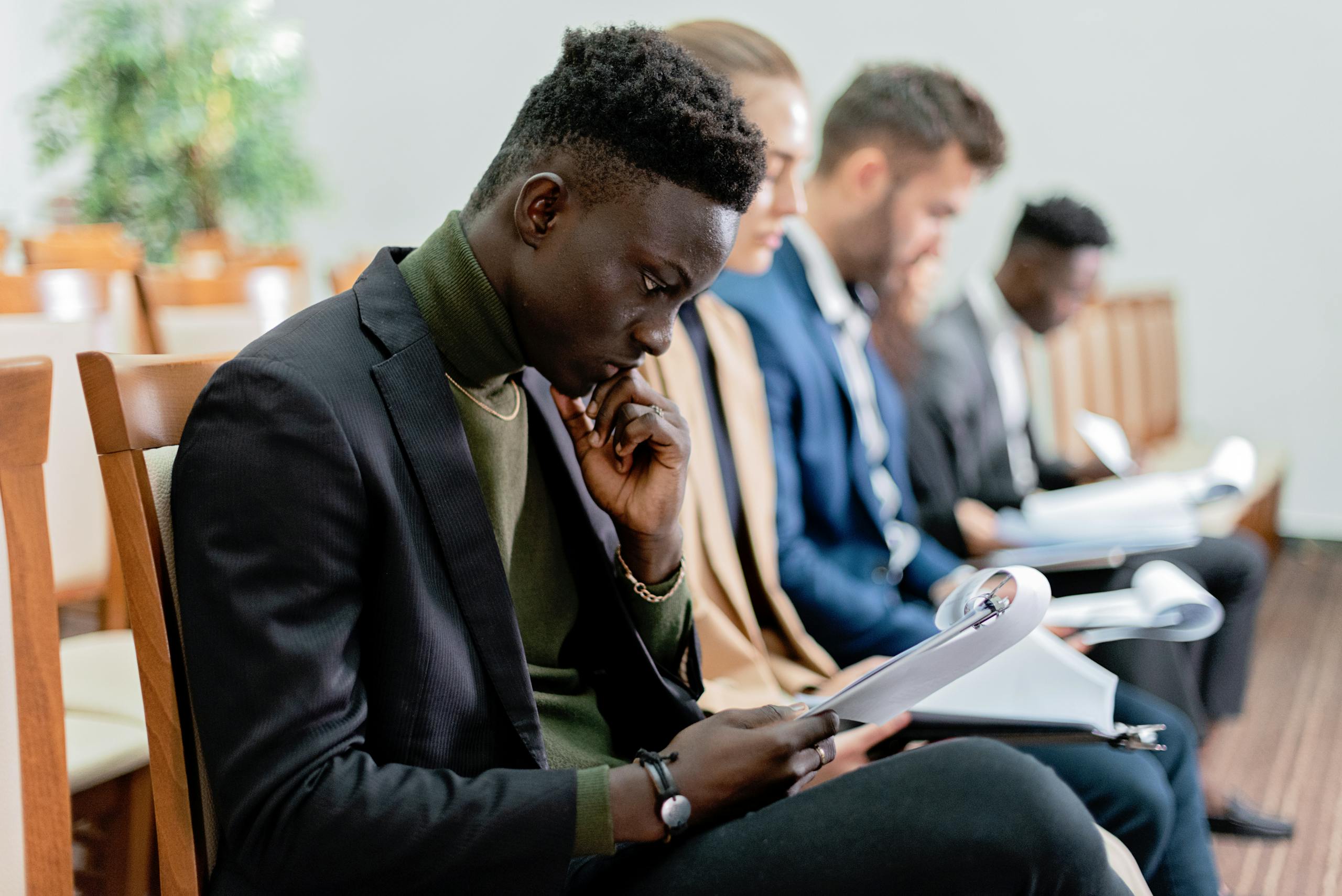 Four diverse professionals in a focused business meeting, reviewing documents in an office setting.