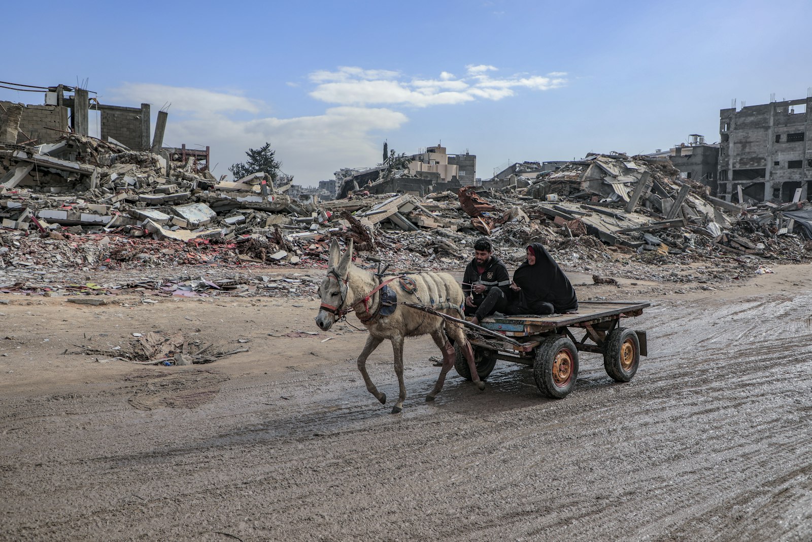 A young man and his mother drive a donkey cart through Jabalia camp