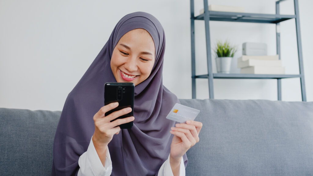 A woman donating online with her phone and bank card at home