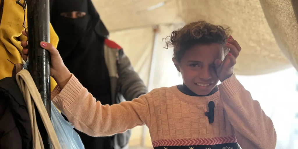A smiling girl with her mother inside their tent in Gaza